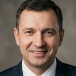 Профессиональный портрет русского бизнесмена, уверенный взгляд, студийное освещение, нейтральный фон.