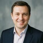 Профессиональный портрет русского бизнесмена, уверенный взгляд, студийное освещение, нейтральный фон.